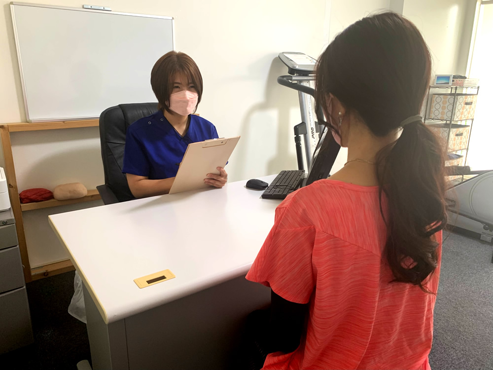 院長がデスクでクライアントのお話を伺っているカウンセリングの様子