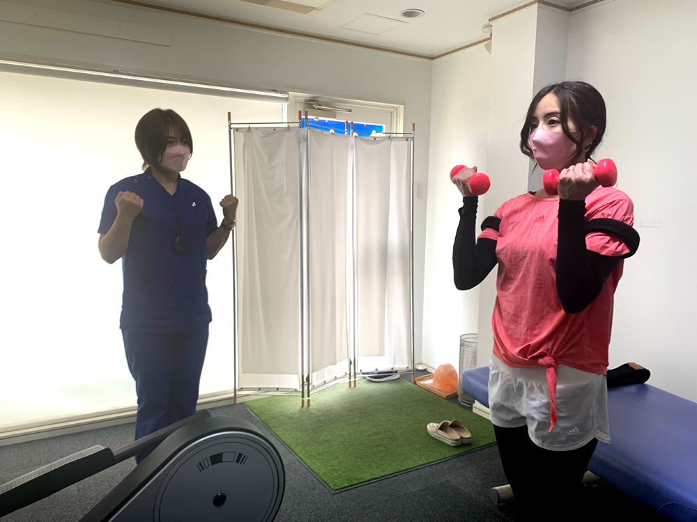 加圧ベルトを着けた女性がダンベルでトレーニングしている様子